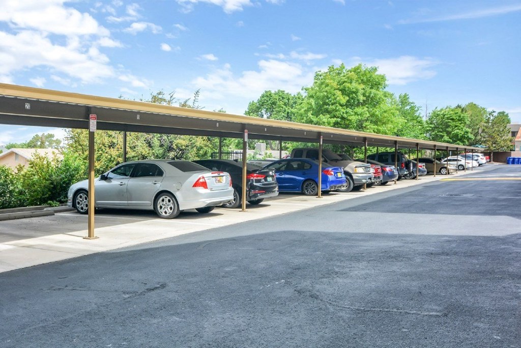A parking lot with cars parked under a covered walkway.
